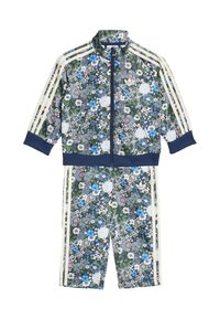 Tepláková súprava s kvetinovým vzorom, obsahujúca zapínaciu bundu a zodpovedajúce šortky. Na tmavozelenom pozadí sú modré, biele a ružové kvety. Po stranách sú biele pruhy.