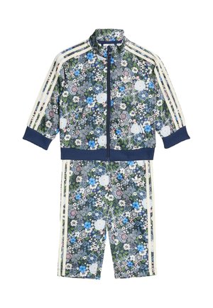 Ensemble de survêtement à imprimé floral avec une veste zippée et un short assorti. Présente des fleurs bleues, blanches et roses sur un fond vert foncé. Des rayures blanches ornent les côtés.
