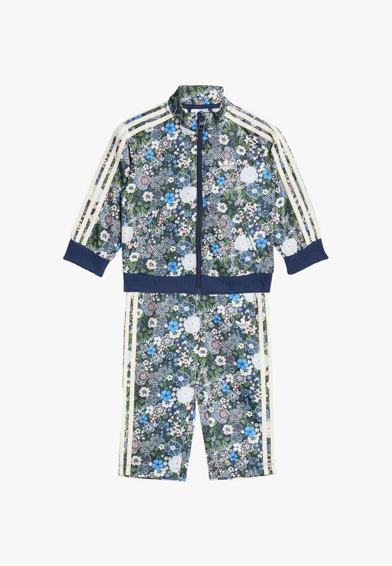 Květinový potisk teplákové soupravy s bundou na zip a odpovídajícími šortkami. Na tmavě zeleném pozadí jsou modré, bílé a růžové květy. Bílé pruhy zdobí boky.