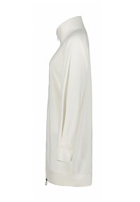 Top bianco a maniche lunghe con colletto alto. Presenta una vestibilità ampia, fessure laterali e un dettaglio con zip sull'orlo inferiore. Tessuto a trama liscia.