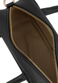 L'interno della borsa in pelle nera presenta una chiusura con zip dorata e una fodera marrone liscia, evidenziando un design strutturato e un ampio scomparto.