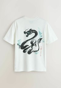 Fehér pamut póló fekete sárkány grafikával, türkizkék díszítésekkel és japán szöveggel a hátoldalon. Rövid ujjú, kerek nyakú.