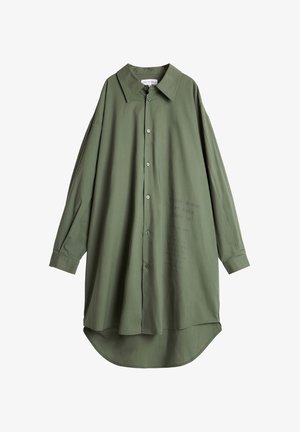 Grønn skjorte, knapp-design, oversized passform, lange ermer, jevn tekstur, buet saum, har trykt tekst på forsiden.