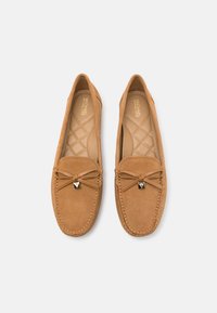 Paire de mocassins en daim beige avec détails cousus, nœud en cuir et semelles matelassées estampillées du logo Michael Kors.