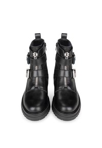 Botas de cuero negro hasta el tobillo con dos cremalleras laterales y correas. Suela gruesa y tacón circular. Textura suave y diseño minimalista.