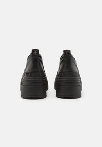 Black platform sneakers with smooth leather upper, textured accents, thick rubber sole, and embossed "BUFFALO" branding on heel.