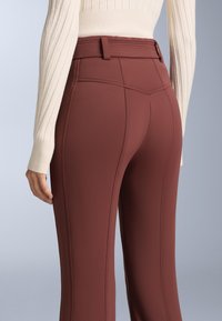 Bordové nohavice s hladkou textúrou, s priliehavým strihom, vertikálnymi švami a rebrovaným pásom.