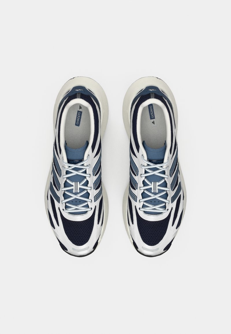 Une paire de chaussures de course bleu marine, blanches et gris clair avec des lacets, vue de dessus sur un fond blanc uni.