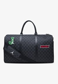 Μαύρη τσάντα duffel φτιαγμένη από υφή υλικό, με πράσινες και κόκκινες κεντητές λεπτομέρειες και αποσπώμενο ιμάντα ώμου. Αξιοσημείωτα λογότυπα.