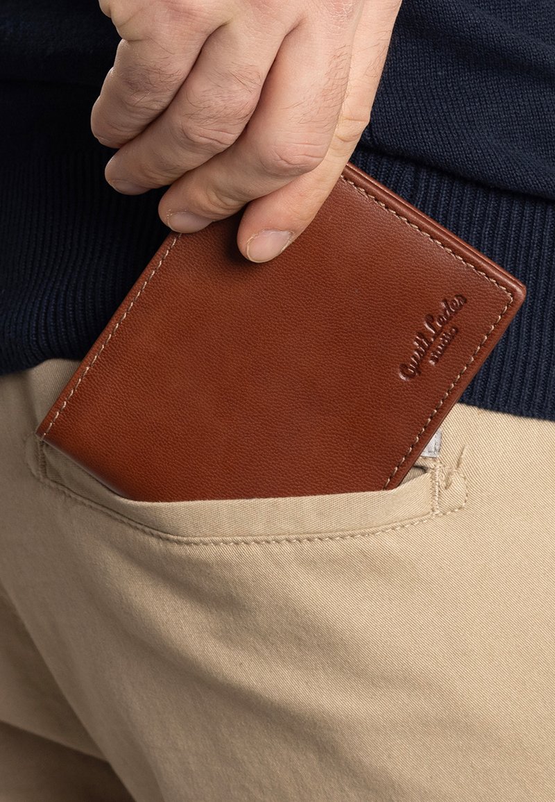 Brown leather wallet partially visible in a beige pocket, featuring smooth texture and a embossed logo on the surface.