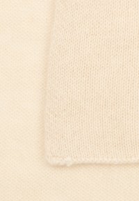 Beiger Strickstoff mit einer weichen Textur, der ein gewebtes Muster und ein gleichmäßiges Finish zeigt, mit ausgefransten Kanten auf einer Seite.