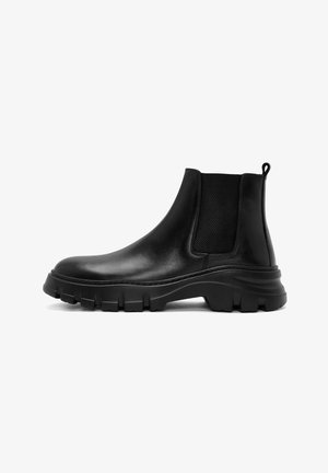 Bottines Chelsea en cuir noir, hauteur à la cheville, panneaux latéraux élastiques, semelle en caoutchouc texturée et languette à l'arrière. Design volumineux.