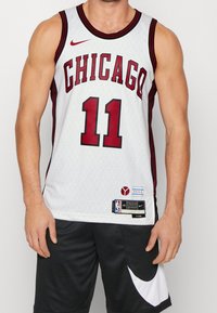 Maillot de basketball Chicago Bulls, blanc avec des accents rouges, présente le numéro 11, le logo Nike, un design texturé, des étiquettes NBA et une ventilation sur les côtés.