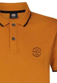 Oranžové polo tričko s černým límečkem a manžetami, se třemi knoflíky a kulatým logem značky vyšitým na levé části hrudi.