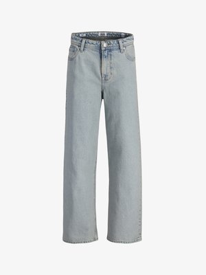 Gutt iført navy blå boblejakke, mørk hettegenser, lyseblå vide jeans og hvite joggesko, stående på en ensfarget lys bakgrunn.