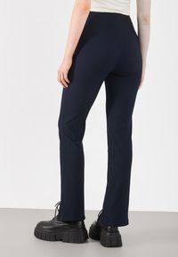 Navy ribbed fabric pants with a fitted design and flared legs, paired with chunky black lace-up platform boots.