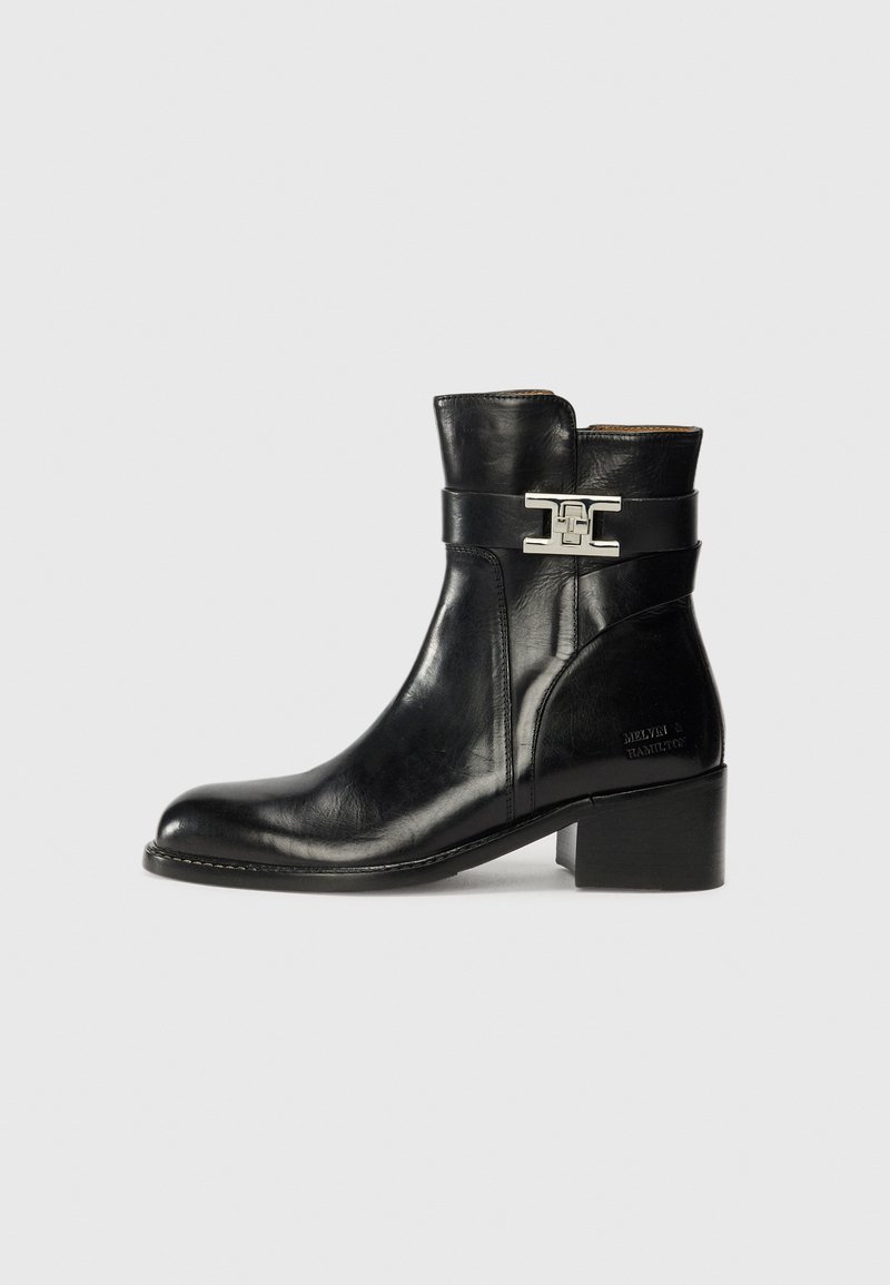 Bottine en cuir noir avec un bout arrondi, accents en métal argenté et un petit talon carré. Comprend une sangle latérale pour une touche de détail supplémentaire.