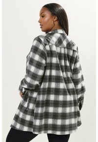 Mustapilkkuinen flanellipaita rentoa istuvuutta, nappikiinnitys, pitkät hihat ja takakappaleen yksityiskohta.