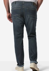 Jeans de denim azul oscuro con cinco bolsillos, costuras claras y corte recto. Con los puños enrollados y un desvanecimiento mínimo para un aspecto limpio.