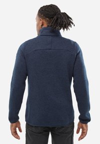 Veste en polaire marine pour homme avec une finition texturée, col montant et manches longues. Caractéristiques d'un ourlet lisse et d'un détail de patte de renfort au dos.