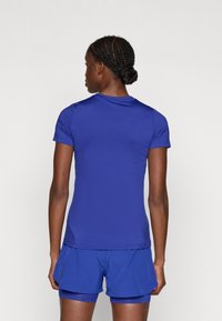 Kék sportpóló rövid ujjakkal és kerek nyakkivágással, sima, könnyű anyagból készült, hozzá illő kék sorttal párosítva.