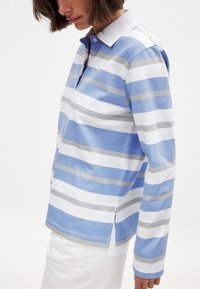 Polo tričko v modro-bielych pruhoch, s golierom, dlhými rukávmi, bočnými rozparkami a mäkkou zmesou bavlny.