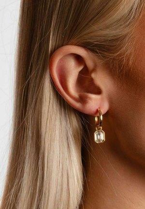 Goldene Creolen mit einem klaren, sechseckigen Edelstein-Akzent. Das Design verfügt über eine glatte Oberfläche und eine sichere Verschlussmechanik.