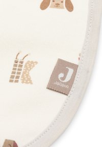 Beige stof met gestikte rand, bedrukt met een honden gezicht en letters, met een bruine merklabel van "Jollein".