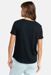 Mørkeblå kortærmet t-shirt med rund hals, featuring opfoldede ærmer og en buet kant. Lavet af blødt, letvægtsstof.