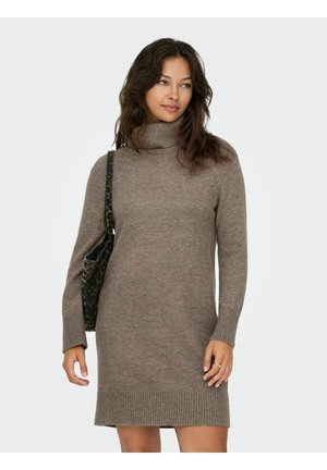 Robe en tricot à col roulé marron clair, dotée de poignets et d'un ourlet à côtes, texture lisse et longueur mi-cuisse. Associée à un sac épaule à motifs.