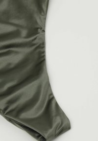 Tissu satin vert olive avec une texture lisse, affichant une forme élégante et sculptée, avec des détails de fronces subtils sur le bord.