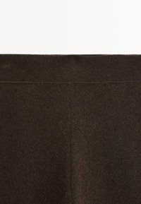 Leggings bruns en tissu lisse et extensible, dotés d'une large taille élastique et de coutures minimales pour un aspect épuré.