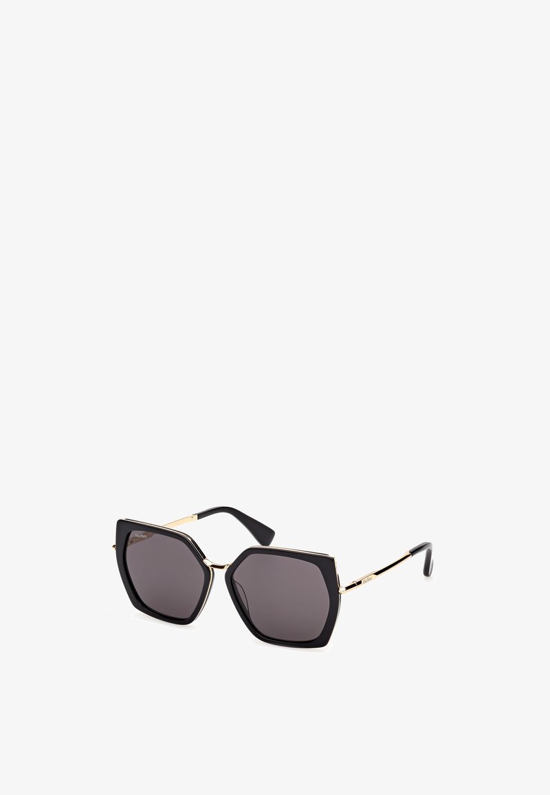 Black octagonal sunglasses with dark lenses; gold metal accents and hinges; glossy plastic frame; sleek, flat arms with a slight curve.