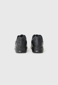 Črne Nike Air superge imajo gladko usnjeno zunanjost, oblazinjen ovratnik in vtisnjen logotip na peti. Oblika je poenostavljena in nizkega profila.