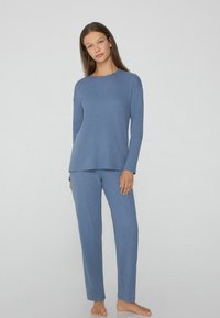 Conjunto de loungewear suave y con relieve en azul claro, que incluye una camiseta de manga larga y pantalones a juego con un ajuste relajado. Tejido ligero y suave.