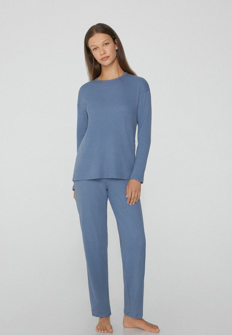 Conjunto de loungewear suave y con relieve en azul claro, que incluye una camiseta de manga larga y pantalones a juego con un ajuste relajado. Tejido ligero y suave.