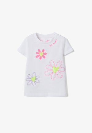 Camiseta blanca de manga corta con tres flores bordadas que tienen corazones verde neón y pétalos rosa y morados, con el texto "LOVE THERAPY" cerca del cuello.