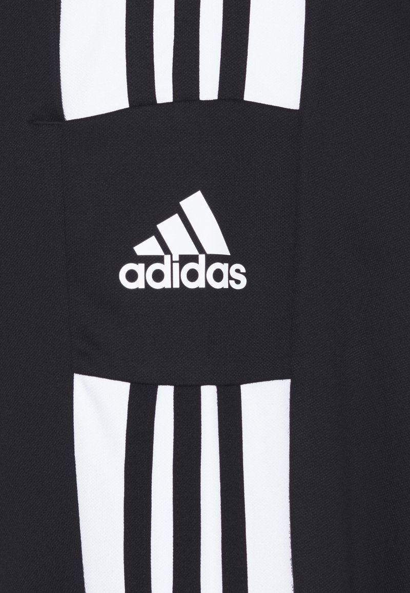 Vêtement de sport noir avec des rayures verticales blanches et une poche arborant le logo Adidas. Fabriqué en tissu texturé.