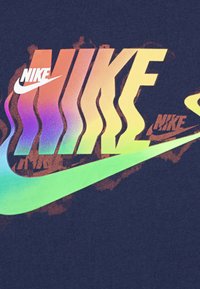 Krátký rukáv, námořnická modrá tričko s vícebarevným logem "Nike" obsahující živé gradienty, víry a ikonický design swoosh.