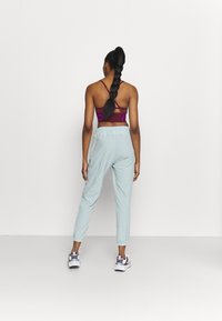 Athletic outfit featuring a dark burgundy racerback sports bra and light blue tapered joggers, with elastic waistband and ankle cuffs.