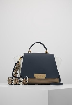 Sort og beige håndtaske med guldspænde, kort håndtag og aftagelig rem prydet med beige og hvide 3D blomsterdekorationer.