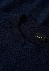 Navyblauer Strickpullover mit runder Halslinie, weicher Textur und gerippten Bündchen. Verfügt über ein schwarzes Etikett mit dem Text "LMTD".