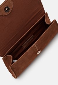 Brun ruskinds pung med knaplukning og glat indvendig foring. Har et mærke indeni og et enkelt, rektangulært design.