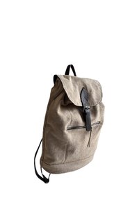 Semišový batoh ve světle šedé barvě s překlopným víkem, černými koženými detaily, přední kapsou na zip a nastavitelnými popruhy.