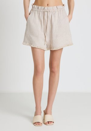 Pantaloncini beige in lino a vita alta con coulisse e tasche frontali indossati con sandali crema con tacco a blocco e punta aperta su modella.