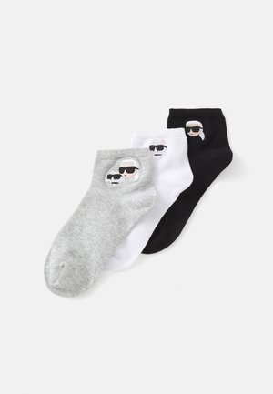 Drei Paar Knöchelsocken: grau, weiß und schwarz, jeweils mit einem aufgestickten Cartoon-Gesicht mit Sonnenbrille auf der Vorderseite. Material aus Baumwollmischung.