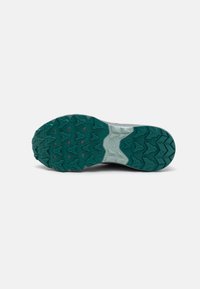 Semelle de chaussure de trail, présentant une semelle extérieure en caoutchouc bleu-vert texturé avec des motifs de traction multidirectionnels et une semelle intermédiaire grise.