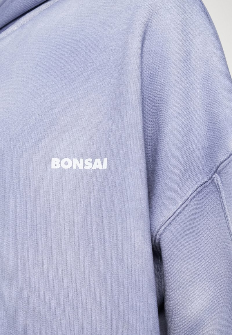 Lavendel sweatshirt med en blød tekstur, der har et hvidt "BONSAI" logo foran. Den har en afslappet pasform og ribbede manchetter.