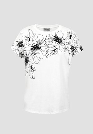 Balta īsroku krekls ar melnu abstraktu ziedu rakstu uz krūtīm un piedurknēm, apaļu izgriezumu un zīmola etiķeti apkakles iekšpusē.