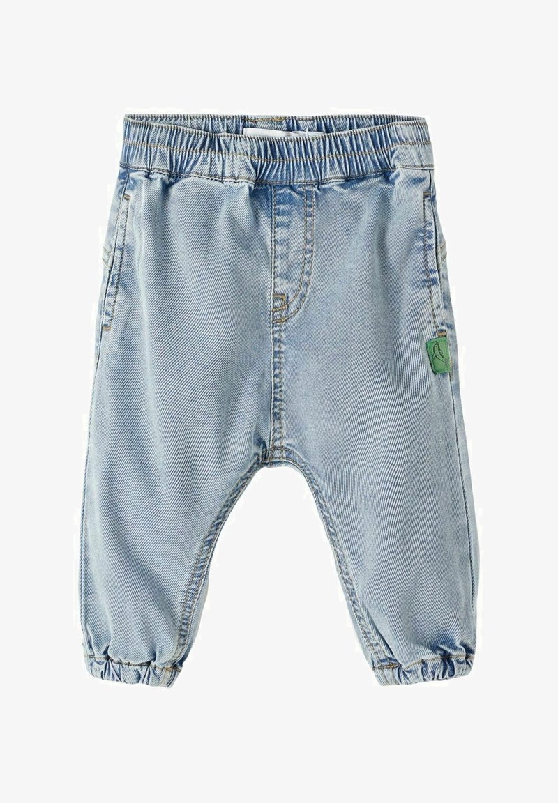 Jean pour tout-petit bleu clair avec taille élastique et ourlet resserré, poches latérales et petite étiquette en tissu verte sur la jambe droite.
